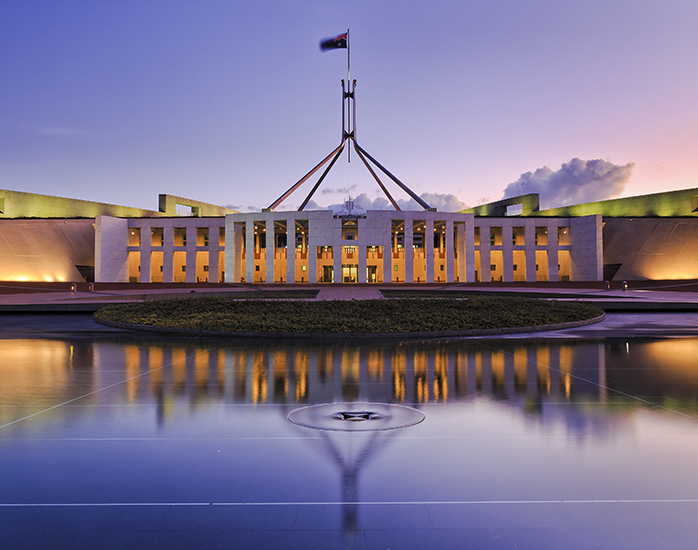 Australian Parliament House lit up at dusk. Fire safety engineering solutions for government and primary industries by Fahrenheit Global.